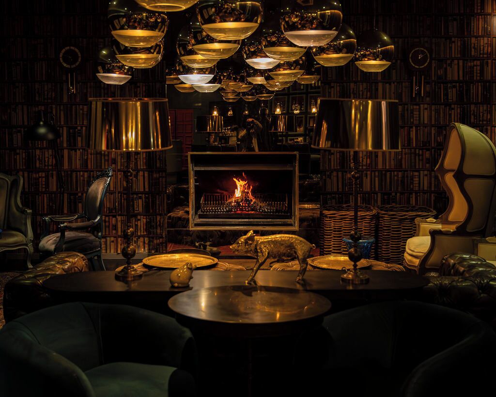 A cozy library with bookshelves, a fireplace, and a dining area with a piggy bank statue.