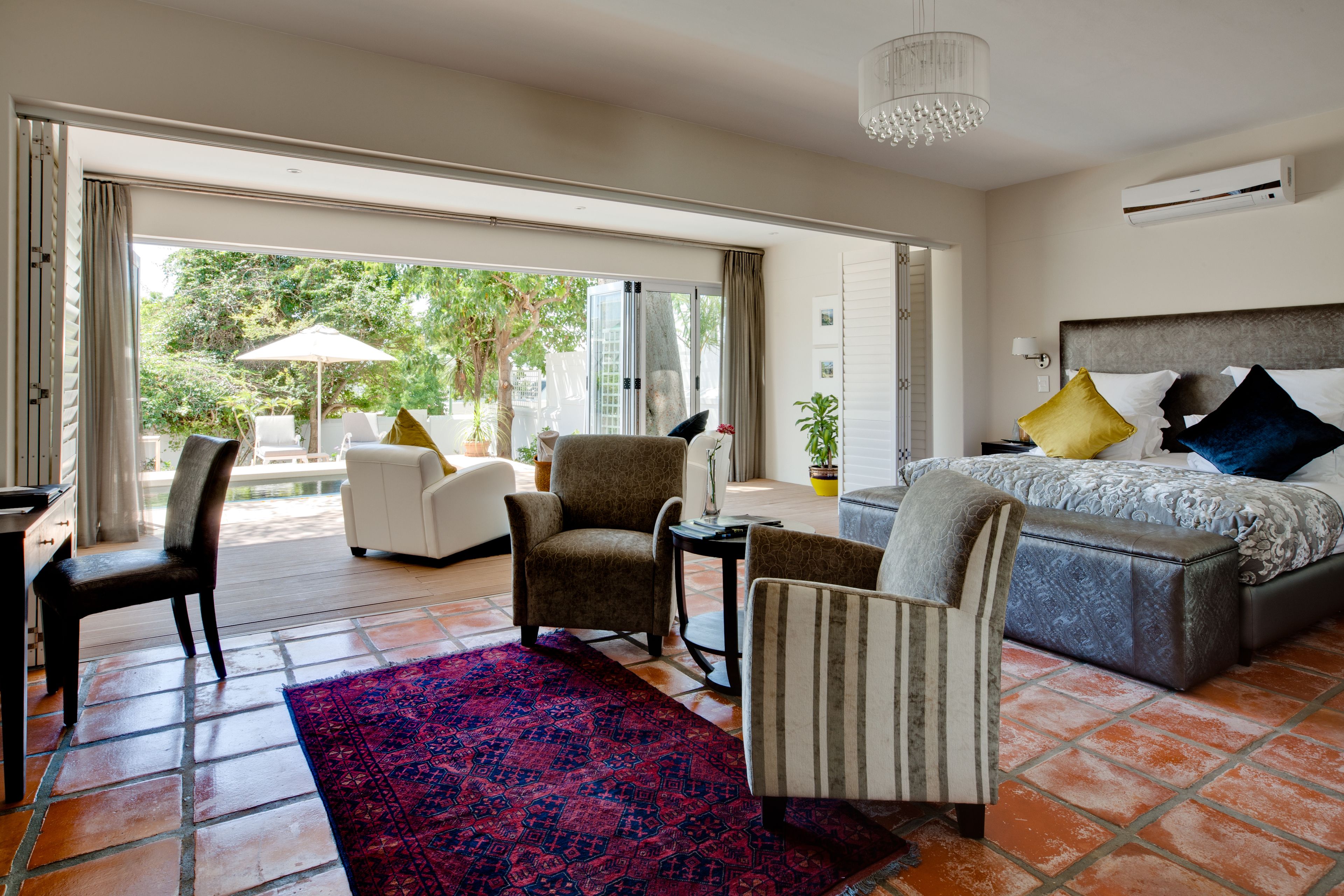 Un dormitorio amplio con una cama grande, un rincón de estar con sillas y vistas al exterior a través de una puerta corrediza.