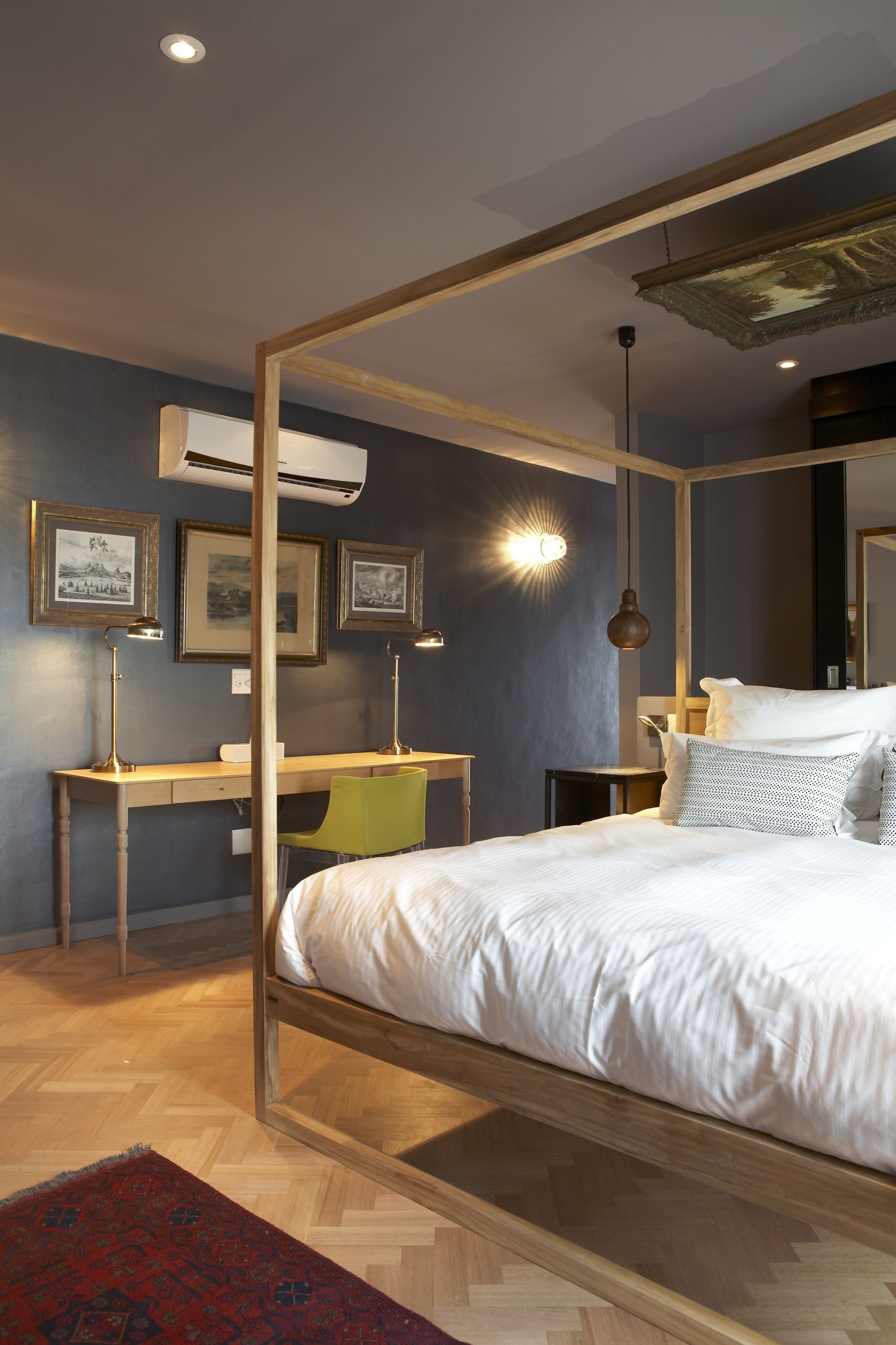A bedroom with a four-poster bed, a desk, and a chair.