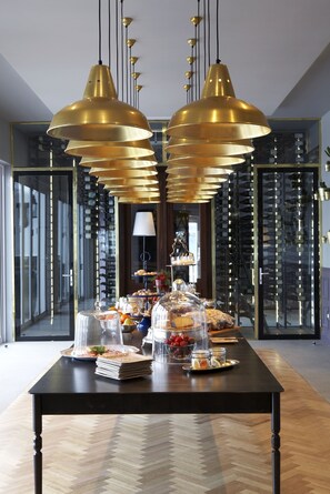 A dining area with a black table set for a buffet, featuring various food items and a wine rack in the background. - Majeka House Boutique Hotel (Stellenbosch)
