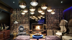 Una biblioteca con estanterías, chimenea y varias lámparas colgantes.