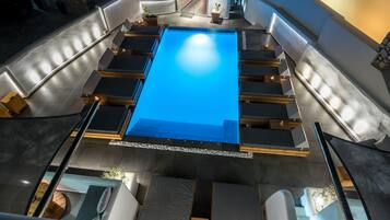 Une piscine sur le toit, dotée de plusieurs espaces aménagés pour s’asseoir et d’un bar.