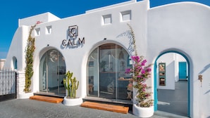 Un edificio blanco con un letrero de 'CALM Collection', ventanas en arco y una puerta azul.