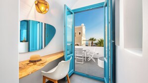 Una habitación moderna con una puerta de marco azul, una silla blanca, una mesa de madera y una lámpara colgante.