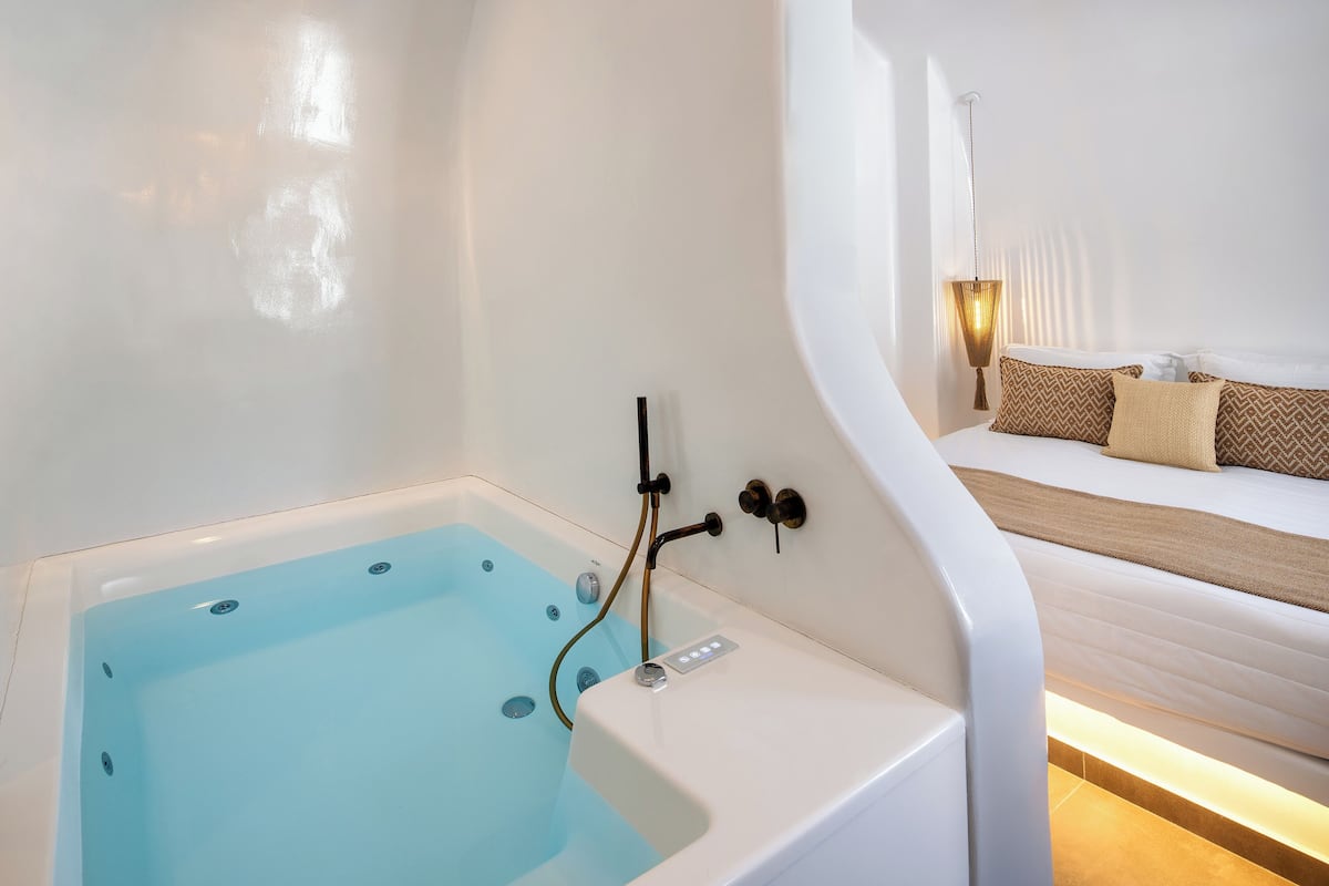 Un baño moderno con bañera, ducha y mesita de noche con lámpara.