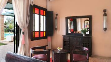 A room with a large window, a mirror, a small table with a bowl, and a sofa.