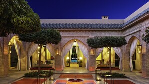 A courtyard with a central pool, surrounded by brick arches and columns, and illuminated by lanterns. - Riad Jawad & Spa (Marrakech)