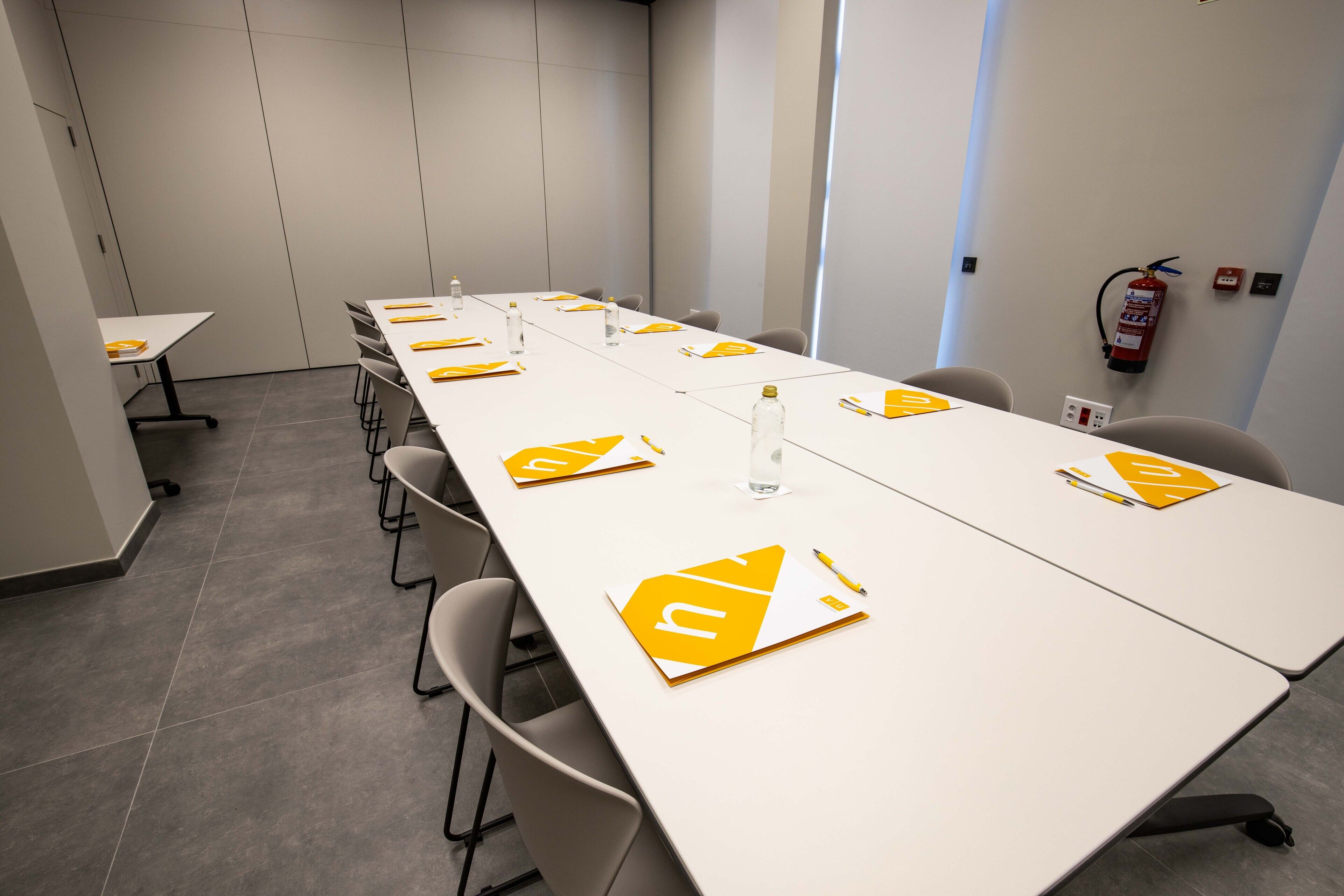 A conference room with a long table, chairs, and a fire extinguisher on the wall.