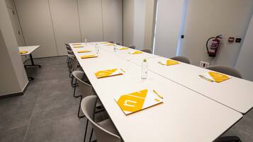 A conference room with a long table, chairs, and a fire extinguisher on the wall.