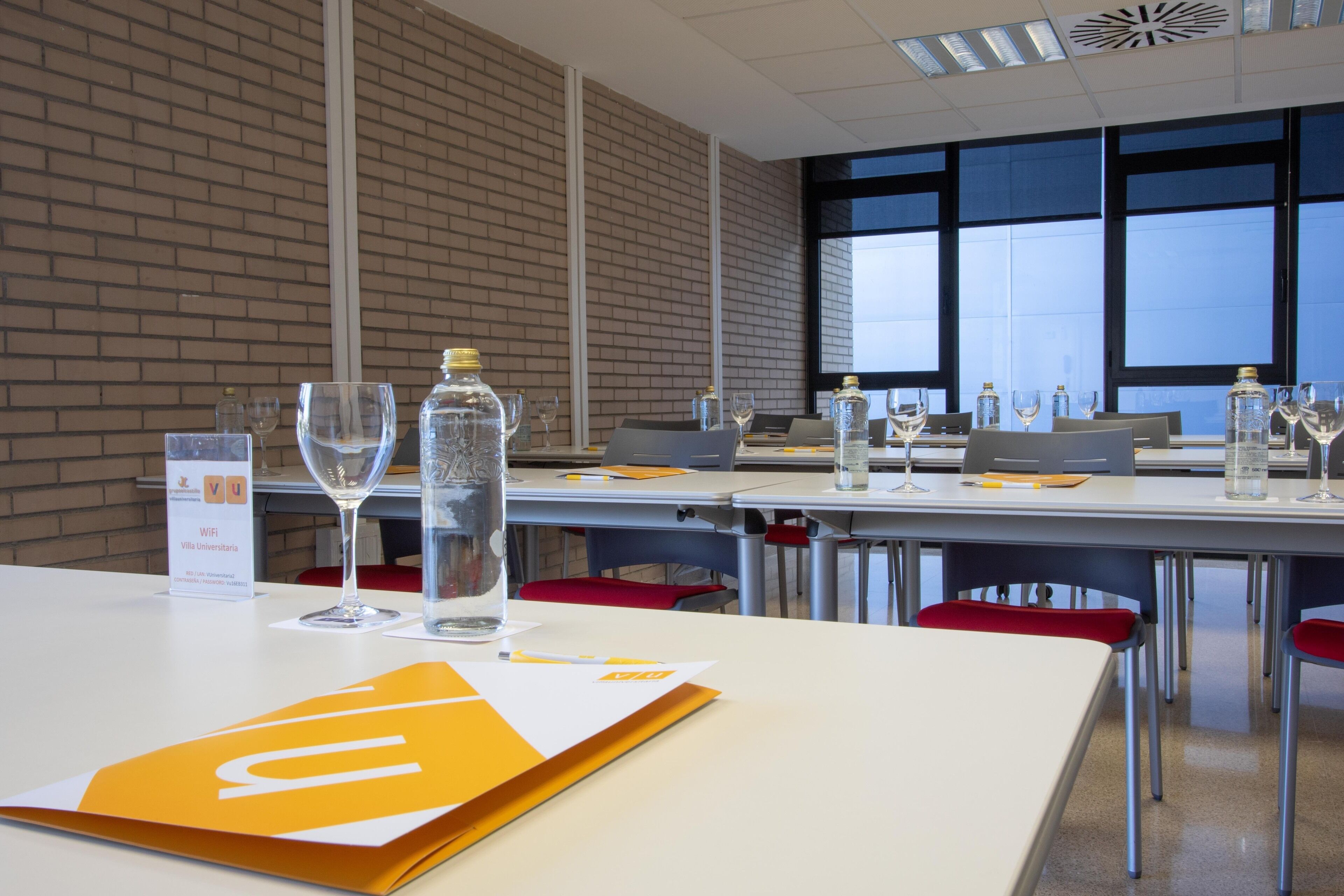 Una sala de conferencias con mesas, sillas y vasos.