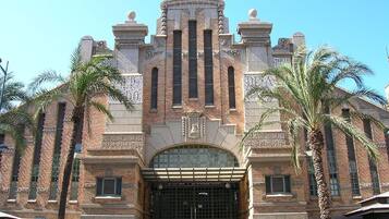 Un edificio histórico con una entrada imponente, que presenta un gran arco de entrada y una fachada simétrica con detalles decorativos.