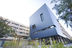 Un edificio moderno con tetto piano, diverse finestre e un mix di materiali per la facciata in bianco e tonalità scure.