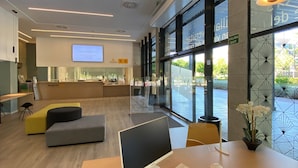 A modern reception area with a reception desk, seating, and a large window offering a view of the outdoors.