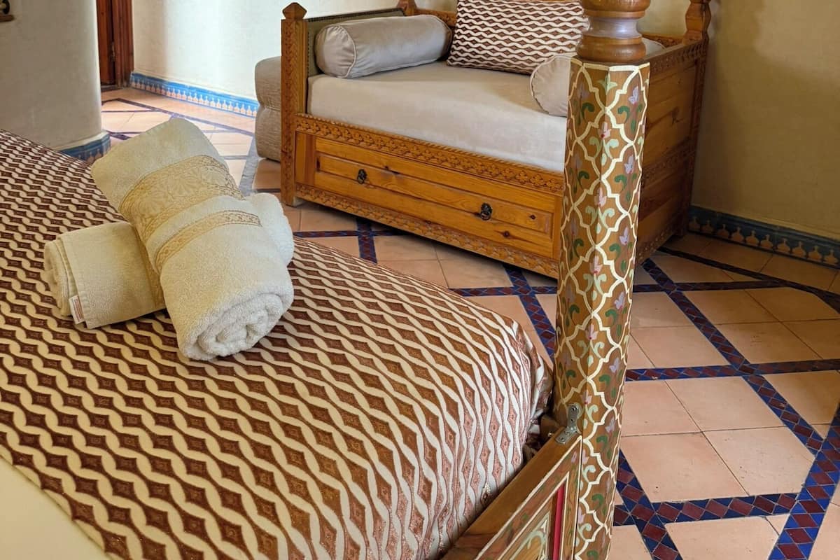 Un dormitorio con una cama, un televisor montado en la pared y un suelo estampado.