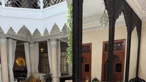 Un salón de estilo marroquí con un sofá verde, baldosas estampadas y muebles de madera ornamentados.