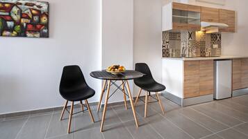 A modern kitchen with wooden cabinets, a built-in oven, and a dining area with a round table and black chairs.