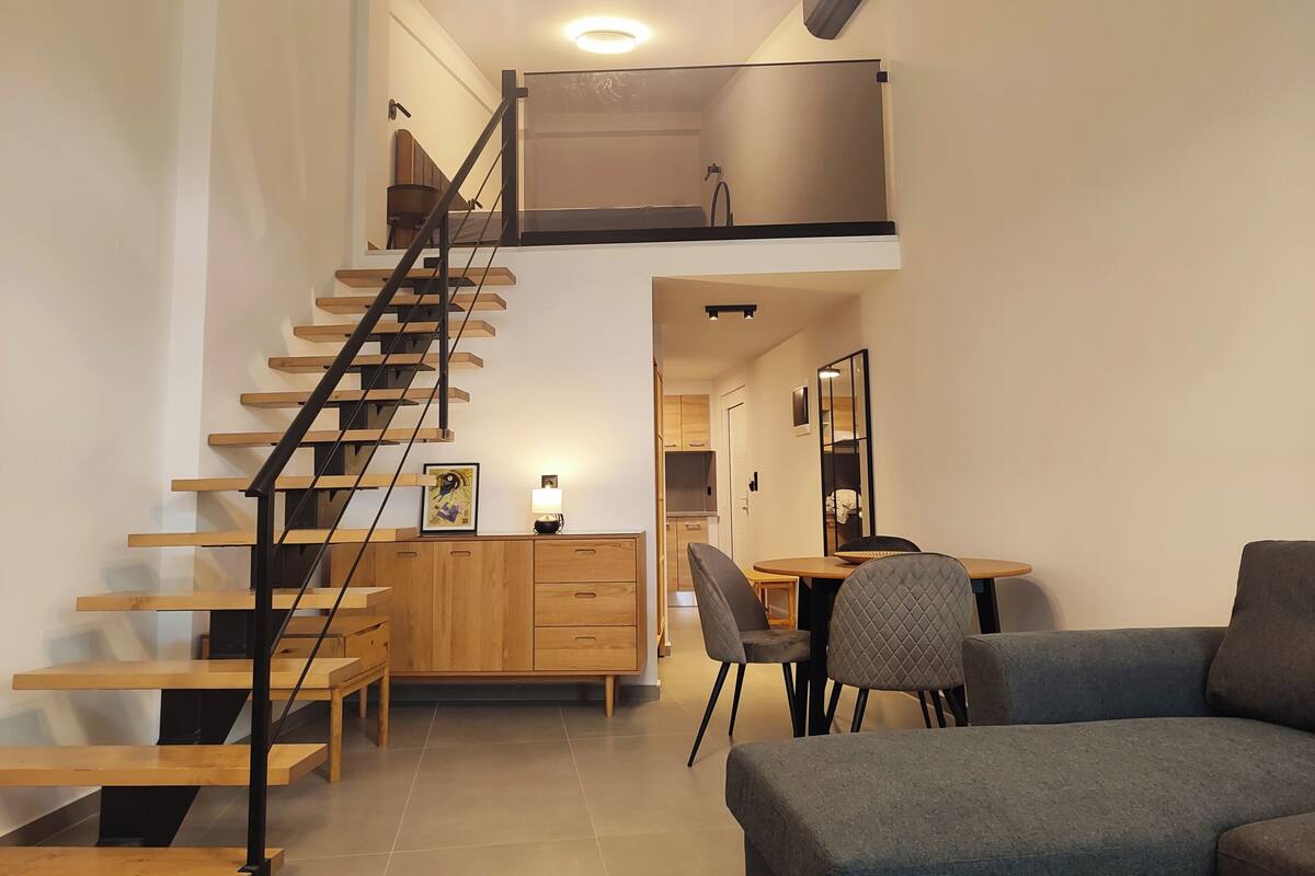 A modern interior with a wooden staircase, a dining area with a table and chairs, and a sofa.