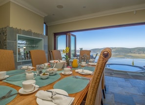 A dining area with a view of a body of water and hills.