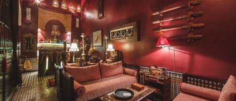 A cozy lounge area with a patterned floor, a sofa set, a coffee table, and a red lamp.