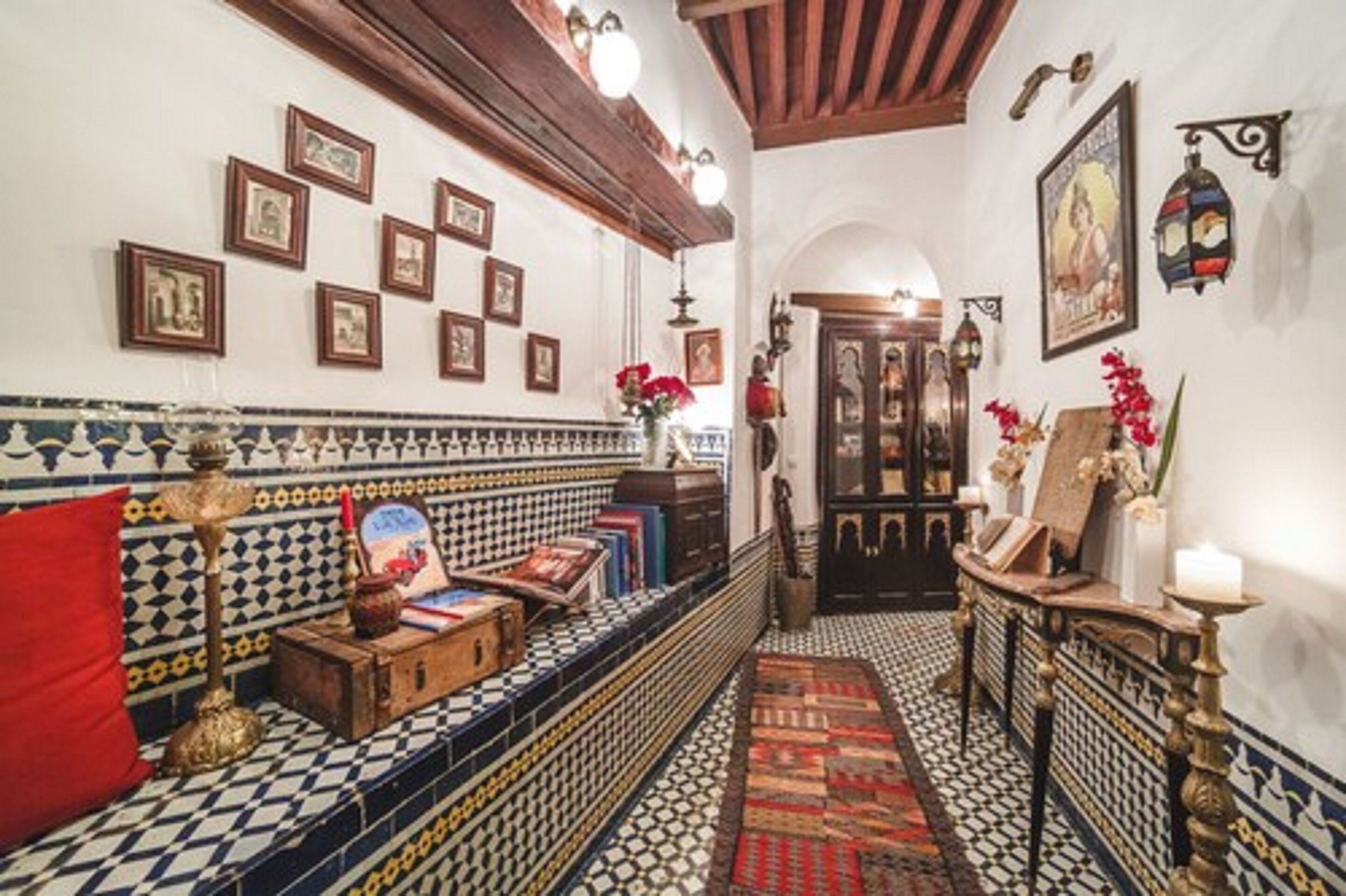 A narrow hallway with patterned tile flooring, a bench with books, and a small table with a candle.