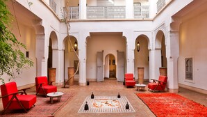Un amplio patio con sillas rojas, una mesa central y una alfombra roja.