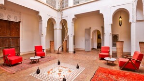 Un amplio patio con sillas rojas, piso a cuadros y arcos decorados.
