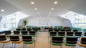 A conference room with rows of chairs, a whiteboard, and large windows.