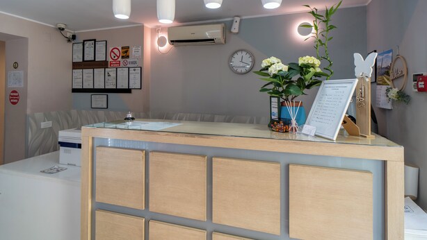 En receptionsdisk med en klocka, inramade dokument och en krukväxt.