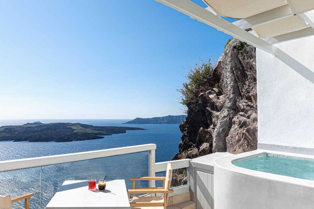 Un balcon avec une table et des chaises donnant sur une piscine et la mer.
