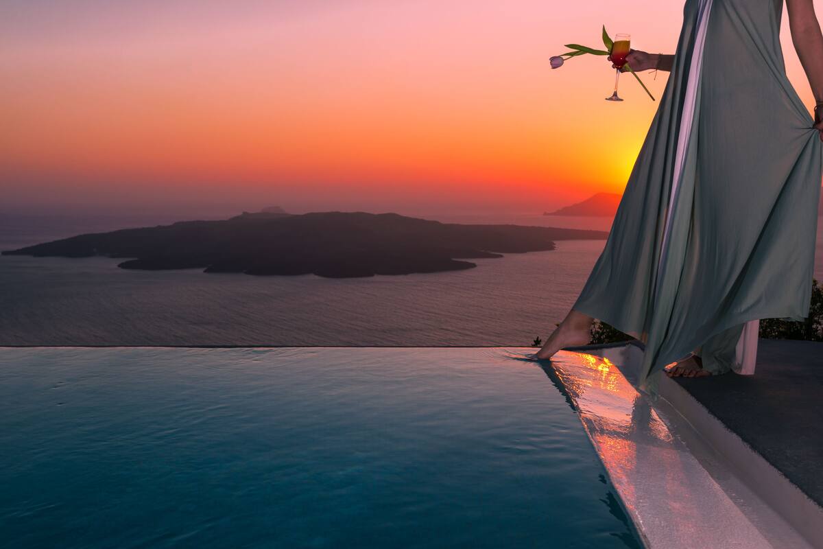 Une vue sur la piscine, avec un coucher de soleil sur l’eau et une île lointaine à l’horizon.