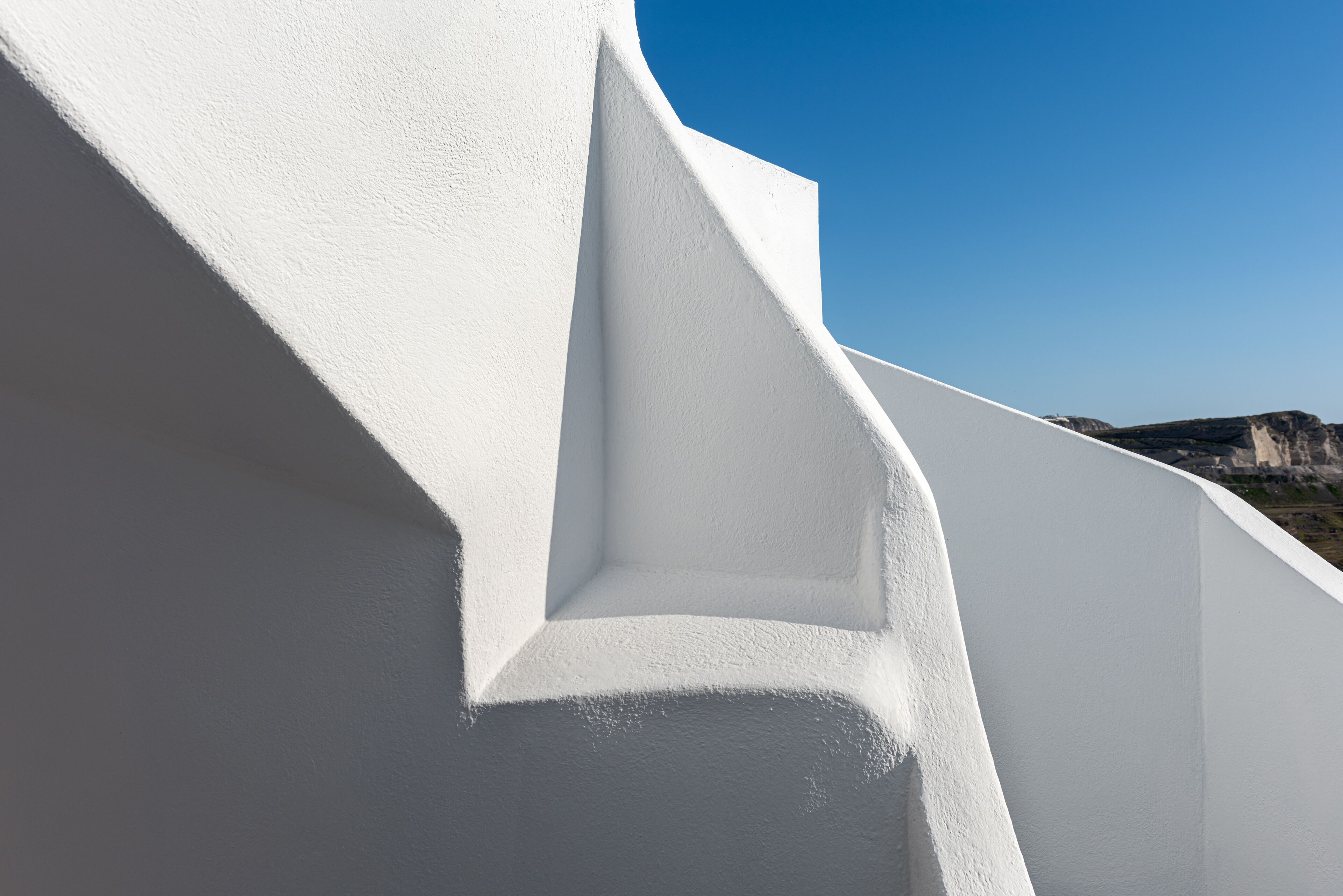 A white building with a steep, angular facade and a clear blue sky in the background.