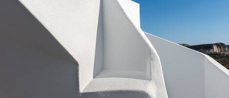 A white building with a steep, angular facade and a clear blue sky in the background.