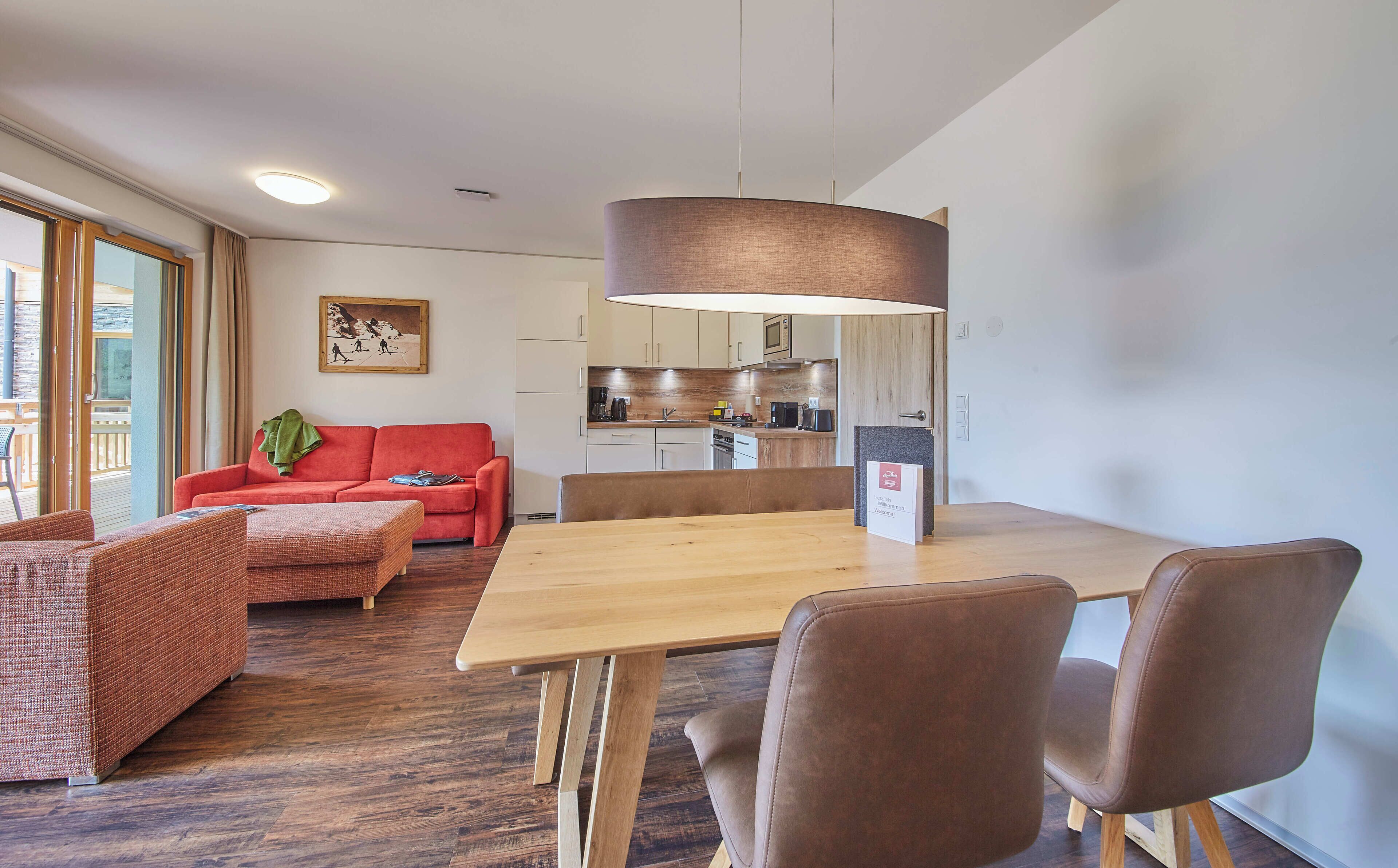 Ein modernes Wohnzimmer mit einem roten Sofa, einem Holzesstisch und braunen Stühlen.