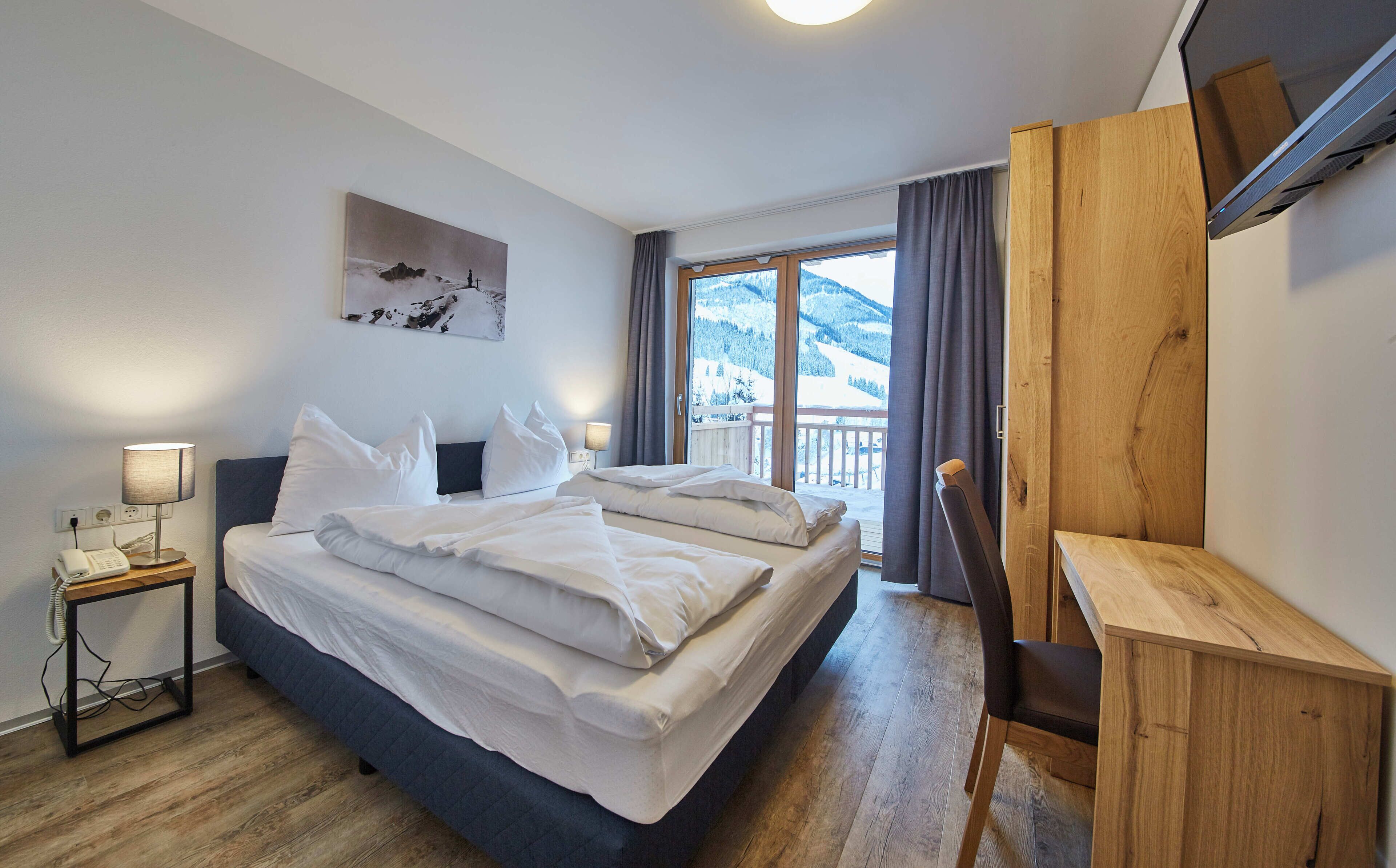 Ett hotellrum med en säng, ett nattduksbord, en lampa och en tavla.