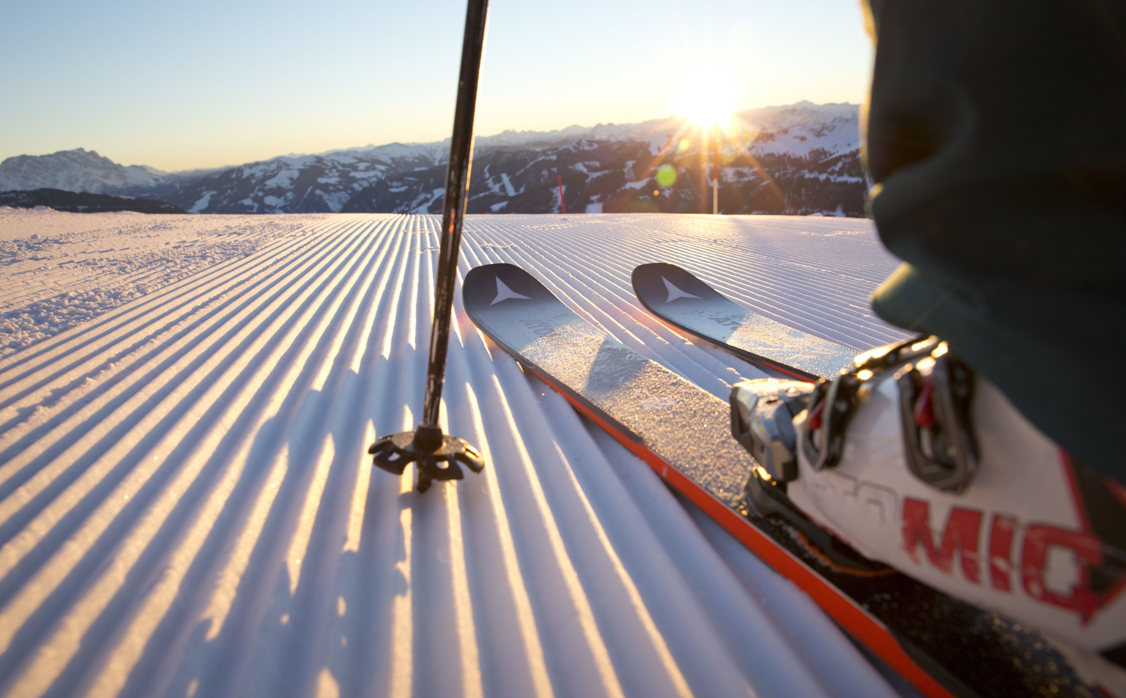 A close-up of ski equipment on a snowy slope with a mountain view in the background.
