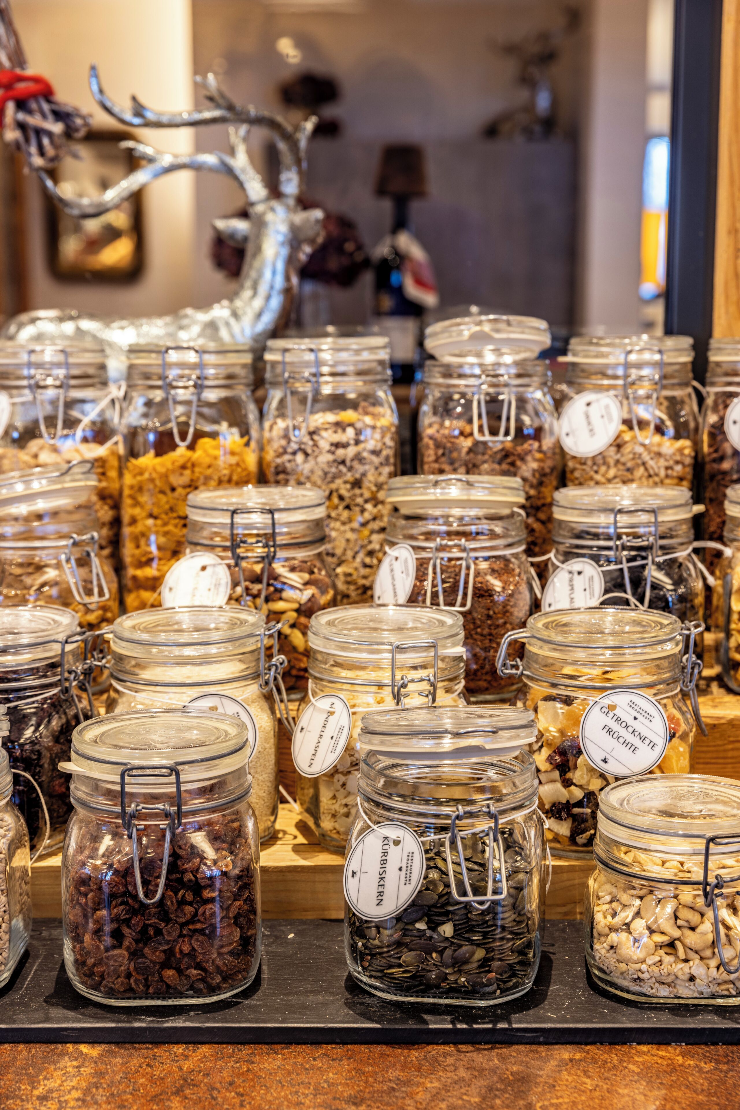 A display of glass jars with metal clasps containing various nuts and seeds.