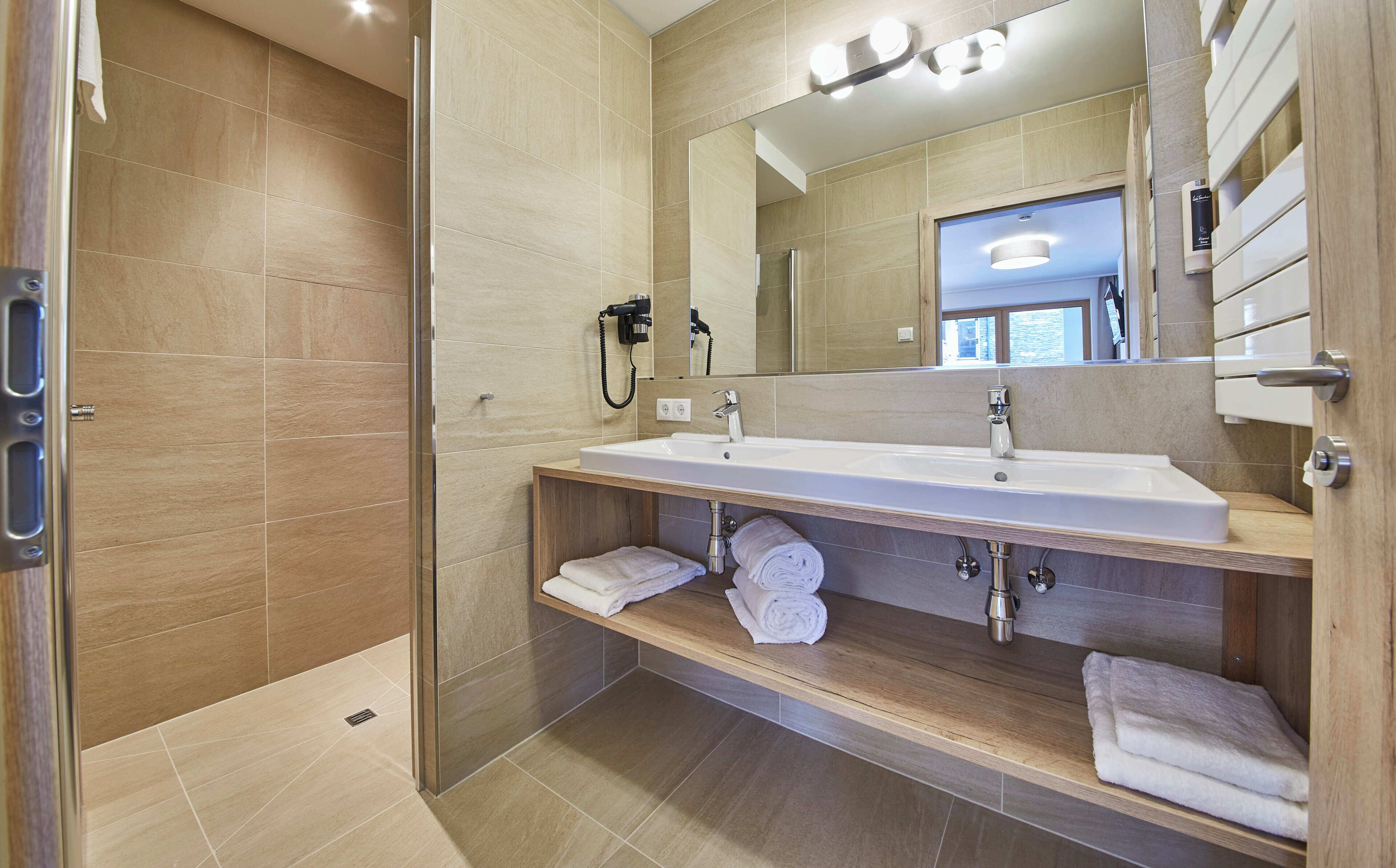 A modern bathroom with a glass-enclosed shower, a double sink vanity, and a mirror above the vanity.