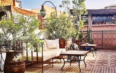 An outdoor dining area with a checkered floor, a sofa, and a table set with food and drinks.