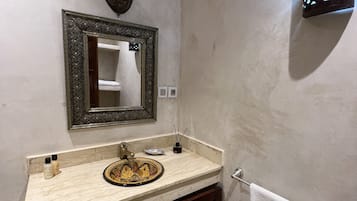 Un baño con lavabo, espejo, toallero y un adorno en la pared.