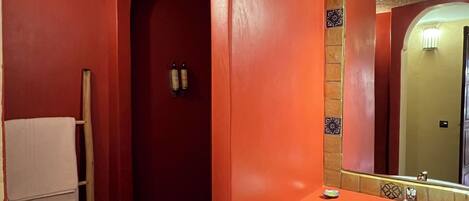 A bathroom with a red wall, a white sink, and a towel rack.