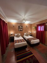 Una habitación de hotel con dos camas, una araña y una alfombra estampada.