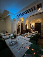 Zona pranzo con tavoli imbanditi per un pasto, caratterizzata da un design tradizionale con archi e un lampadario.