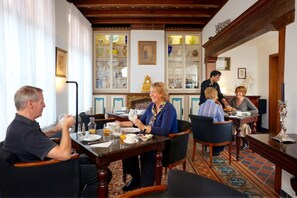 Un comedor con mesas y sillas de madera, suelo estampado, y una exhibición de cristalería y cerámica.