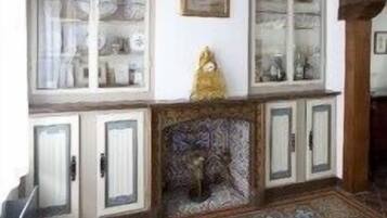 Une pièce dotée d’un sol à motifs, d’une cheminée et d’un meuble vitrine aux portes en verre.