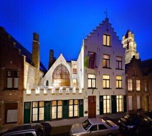 A building with a prominent arched entrance, multiple windows, and a tower-like structure. - Huis 't Schaep (Bruges)