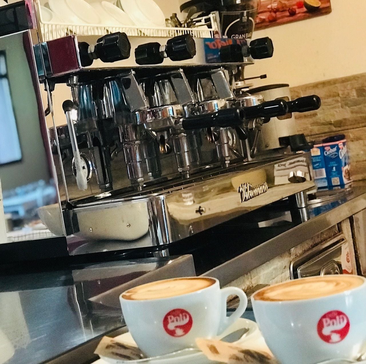 A coffee machine with multiple portafilters and a branded coffee cup.
