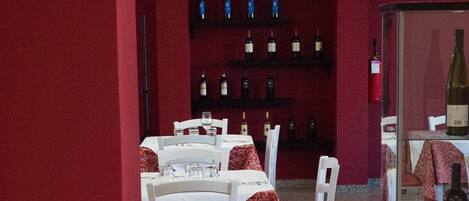 A restaurant with tables set for dining, a wine rack with bottles, and a barrel in the foreground.