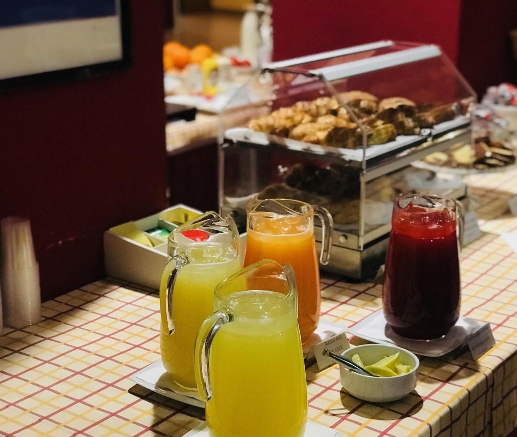 A buffet with various food items and beverages, including a fruit punch and a red drink.