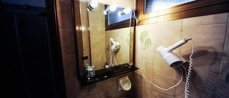 A bathroom with a sink, mirror, hairdryer, and a shelf with a cup and a tissue box.