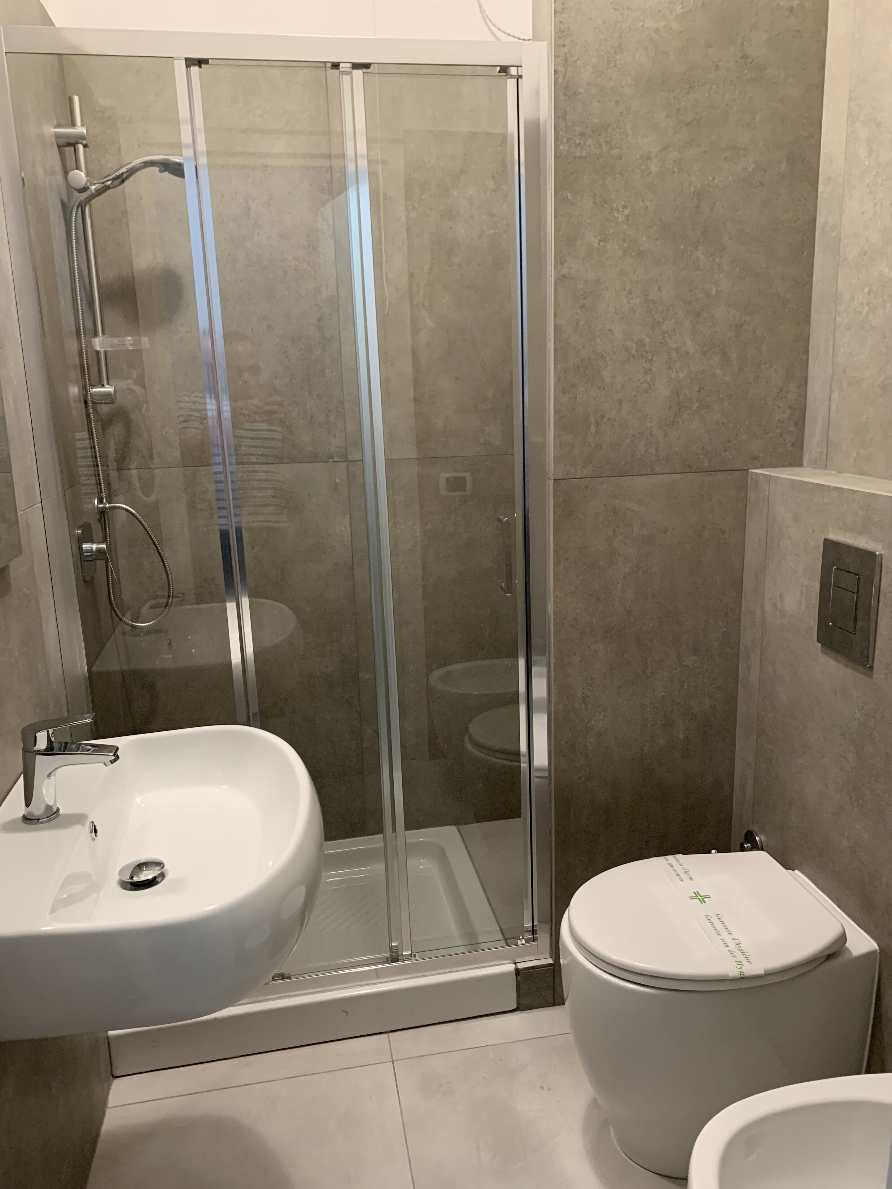 A bathroom with a glass-enclosed shower, a white sink, and a toilet.